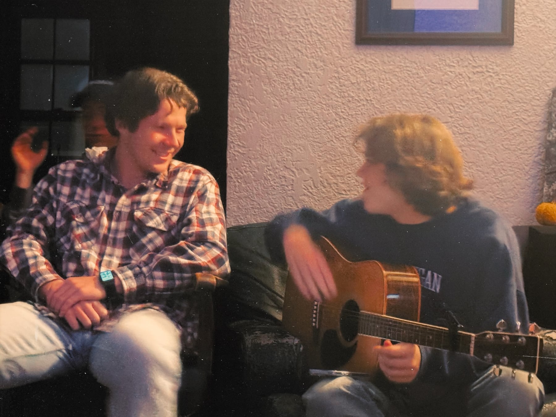 Two friends talking while one holds a guitar in the Dutch House